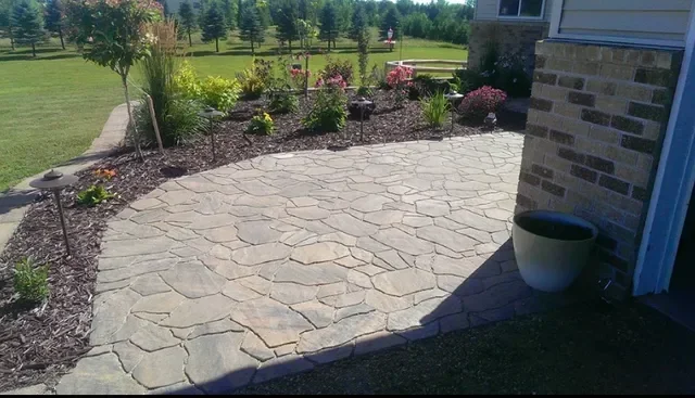 Flagstone patio with irregular stone pavers and adjacent mulch landscape bed with shrubs