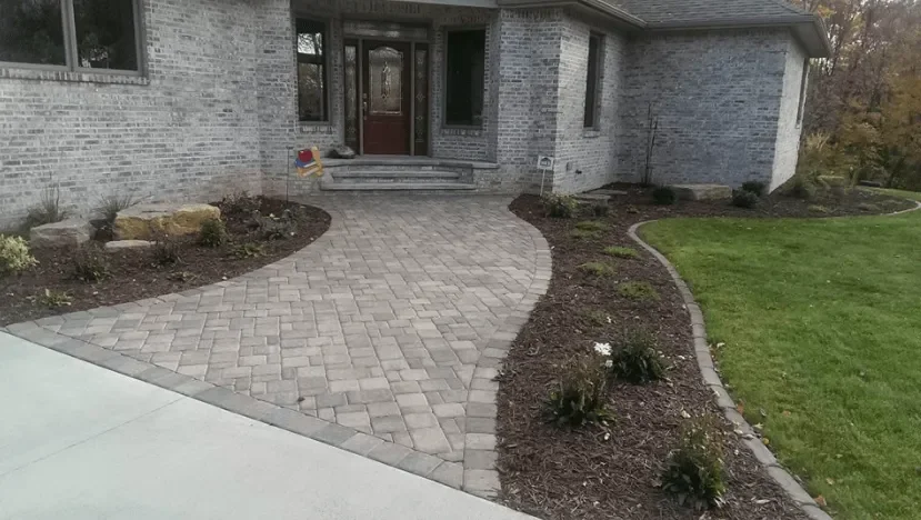Curved herringbone paver walkway with mulched planting beds and landscape design