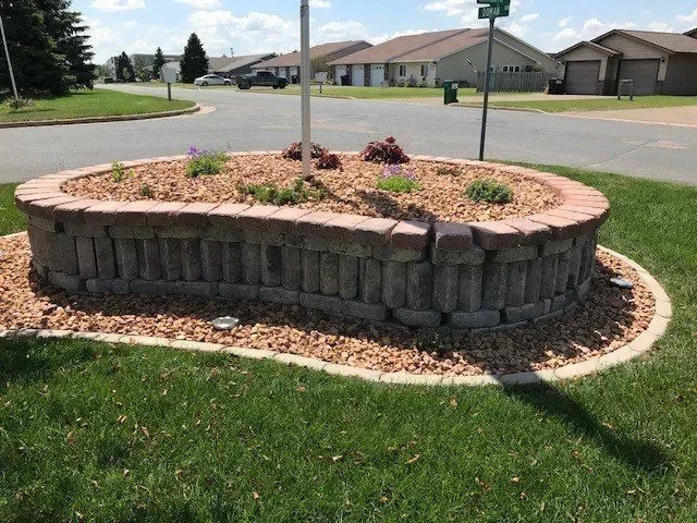 Timber-edged landscape bed with river rock mulch and ornamental plantings