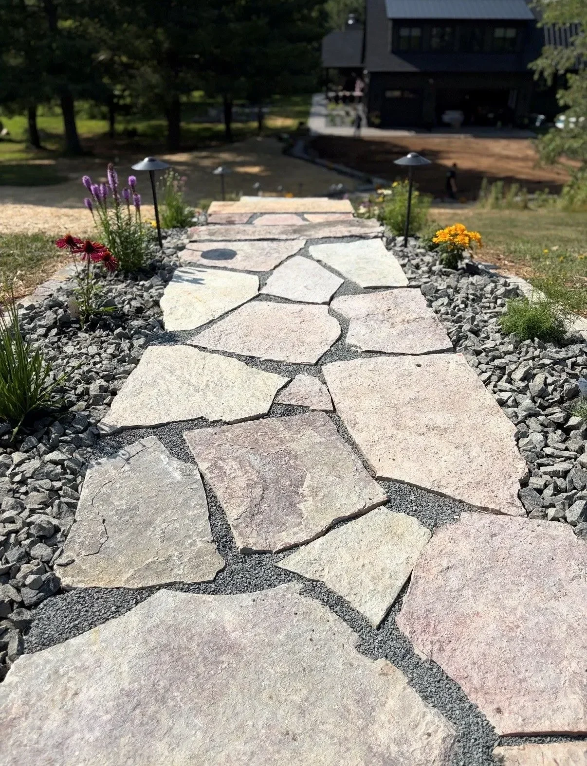 Flagstone pathway with river rock borders, landscape lighting, and flowering perennial plantings
